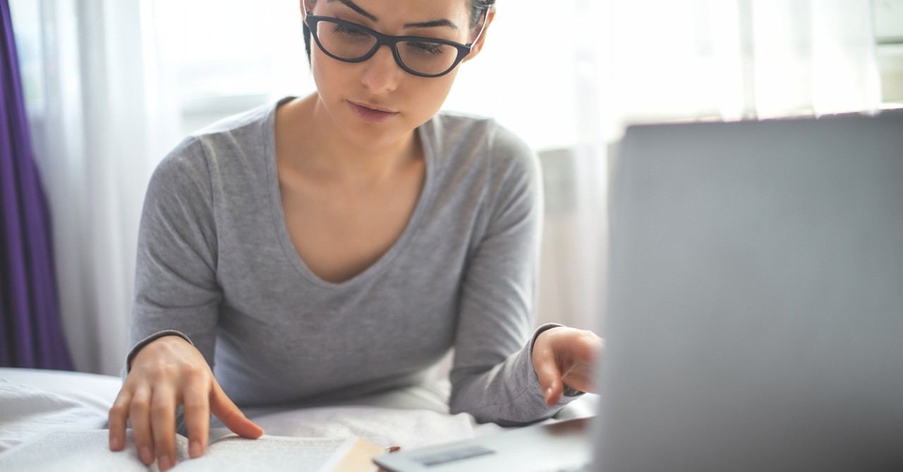 woman on laptop with smartphone and Bible, impact of technology on christian living and worship