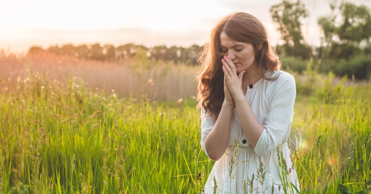 Woman praying in a field of flowers