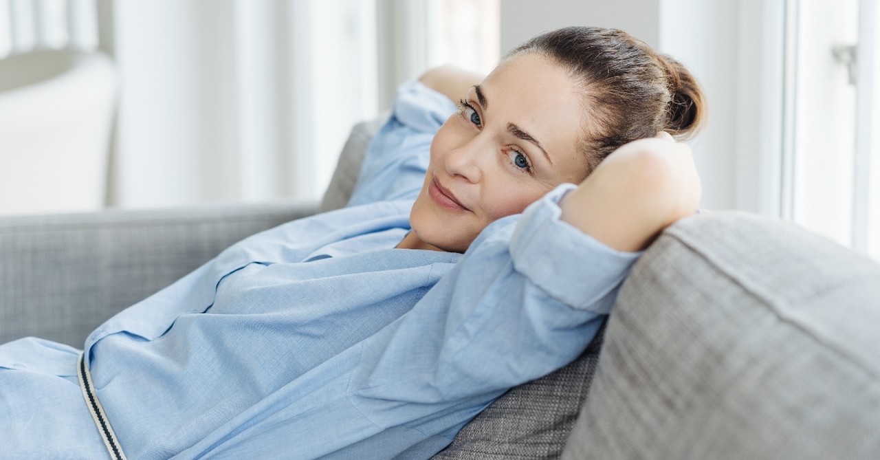 woman looking at camera sitting on couch relaxing, do you struggle with sin of acedia