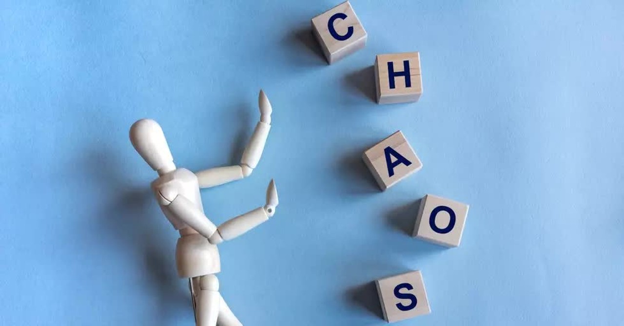 wooden person holding back the word chaos in letter cubes