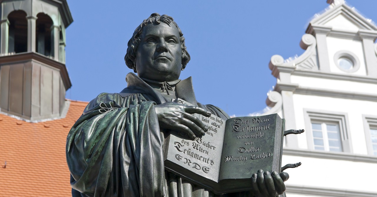 statue of Martin Luther holding book in front of church, Martin Luther and his 95 theses