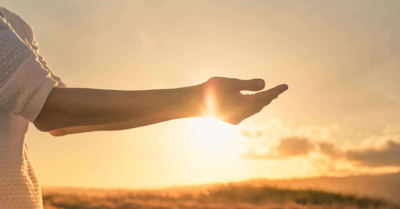 woman arms out at sunrise giving burdens to God