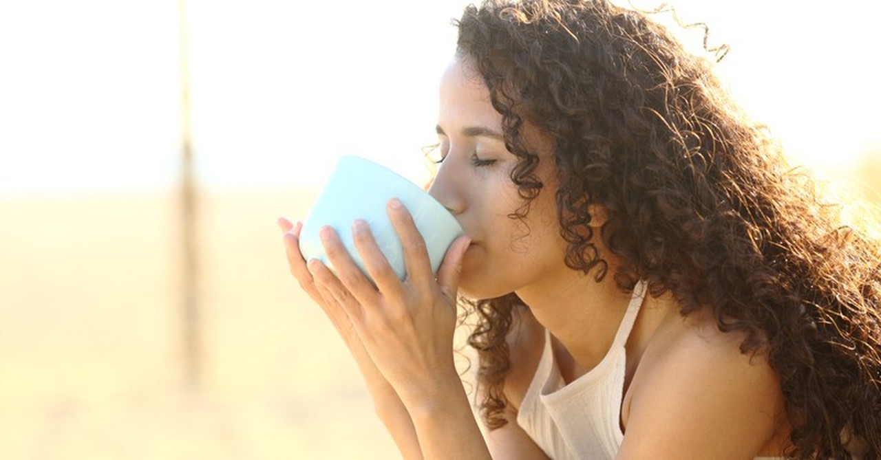 young woman drinking coffee outdoors at peace