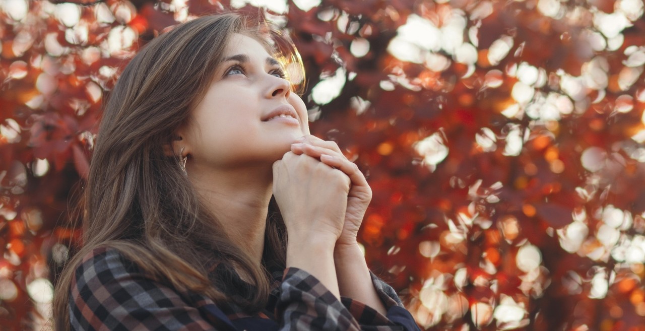 Woman praying near some fall leaves