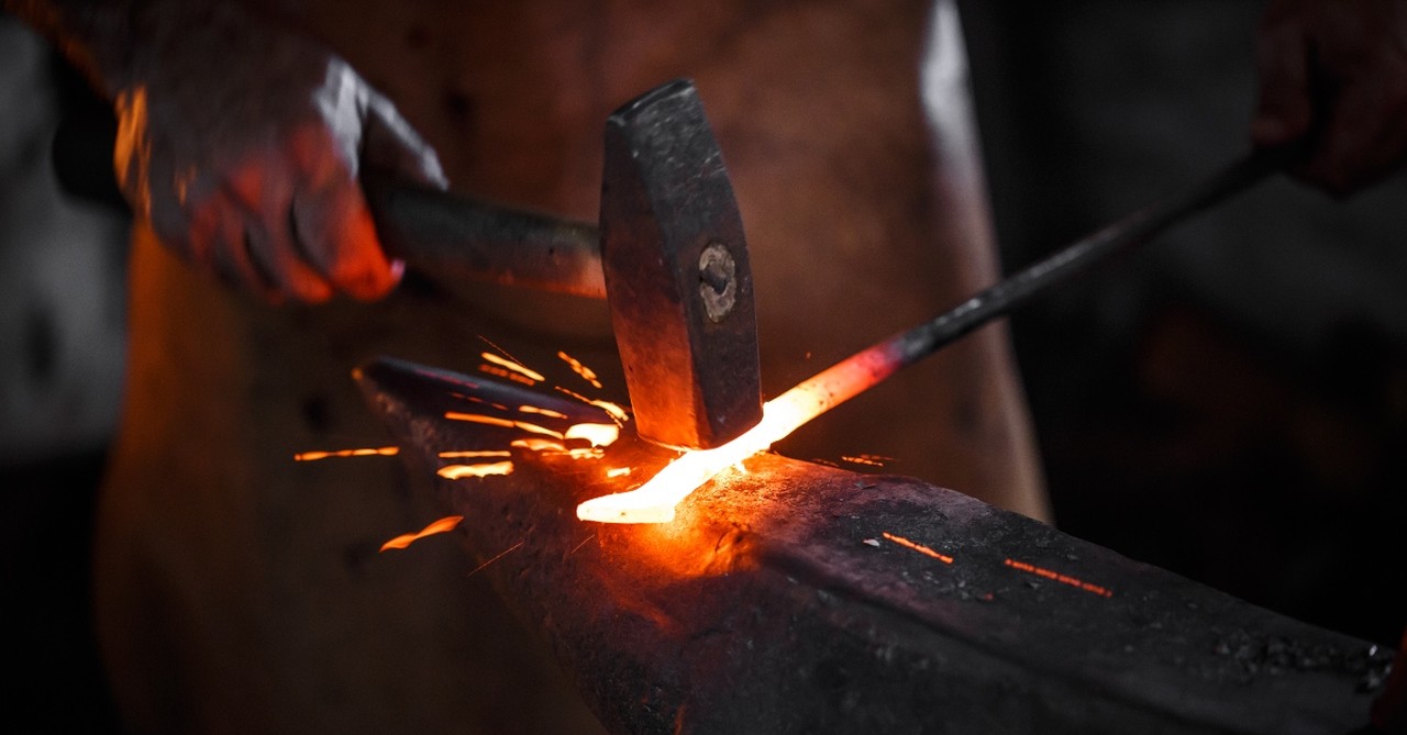 Blacksmith working a piece of metal, refiner's fire