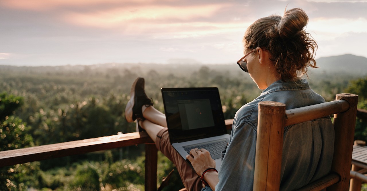 woman working on laptop overlooking a beautiful scenery outside