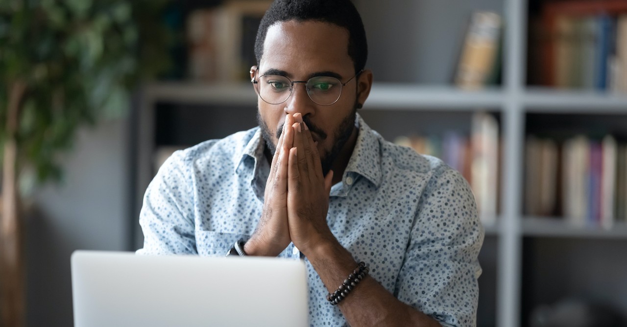 Man staring at computer screen looking stressed, fear of good news