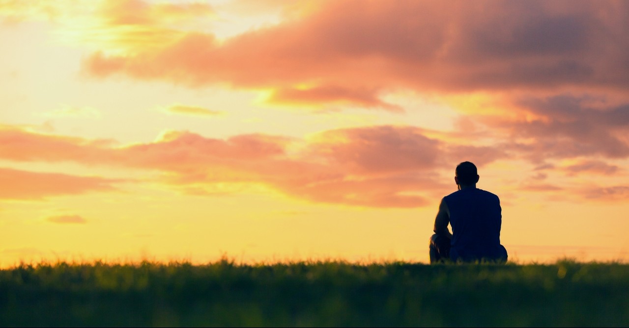 Man sitting still looking at the sunset