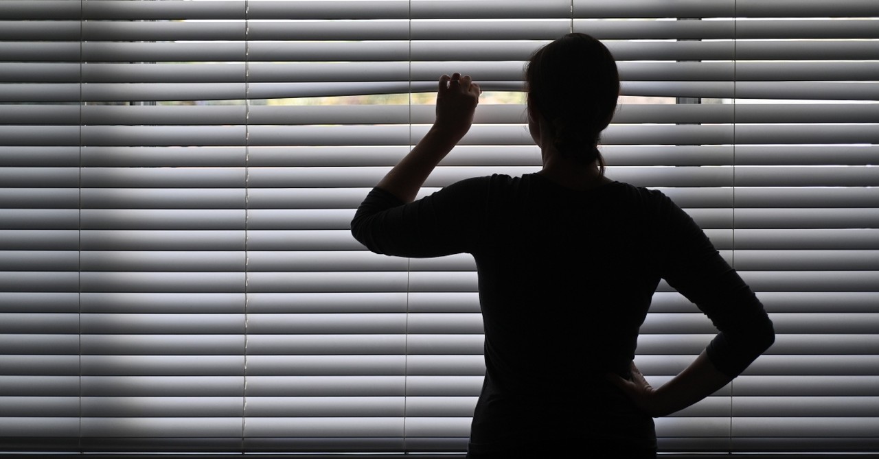 Woman spying out the window blinds