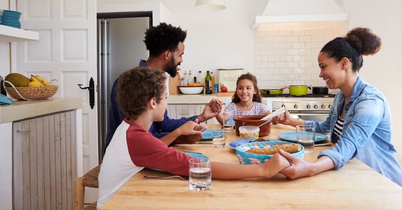 family praying around dinner table with kids