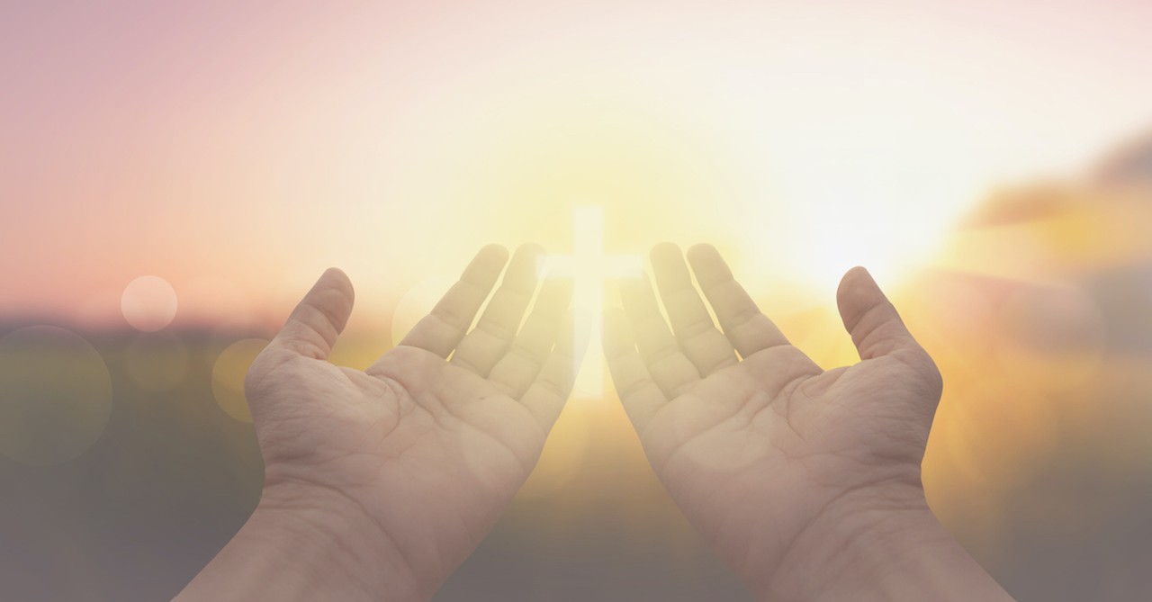 open prayer hands with concept of cross in bright light outside, thankfulness challenge