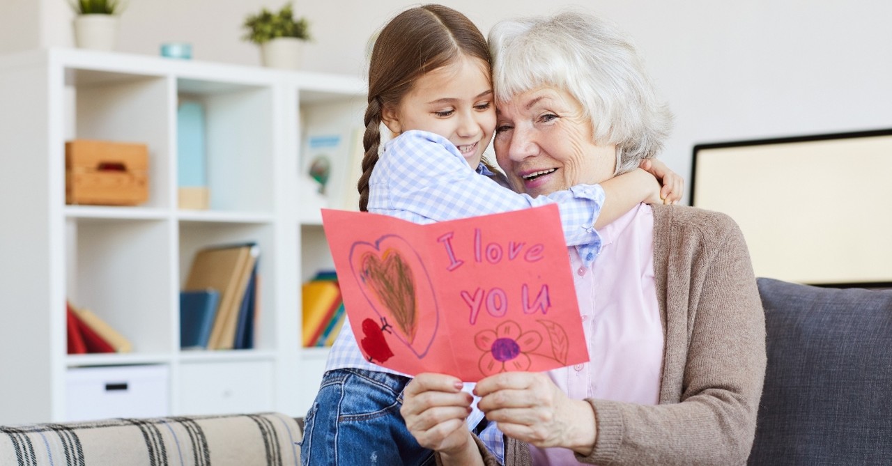 granddaughter hugging her grandmother giving her a valentines card