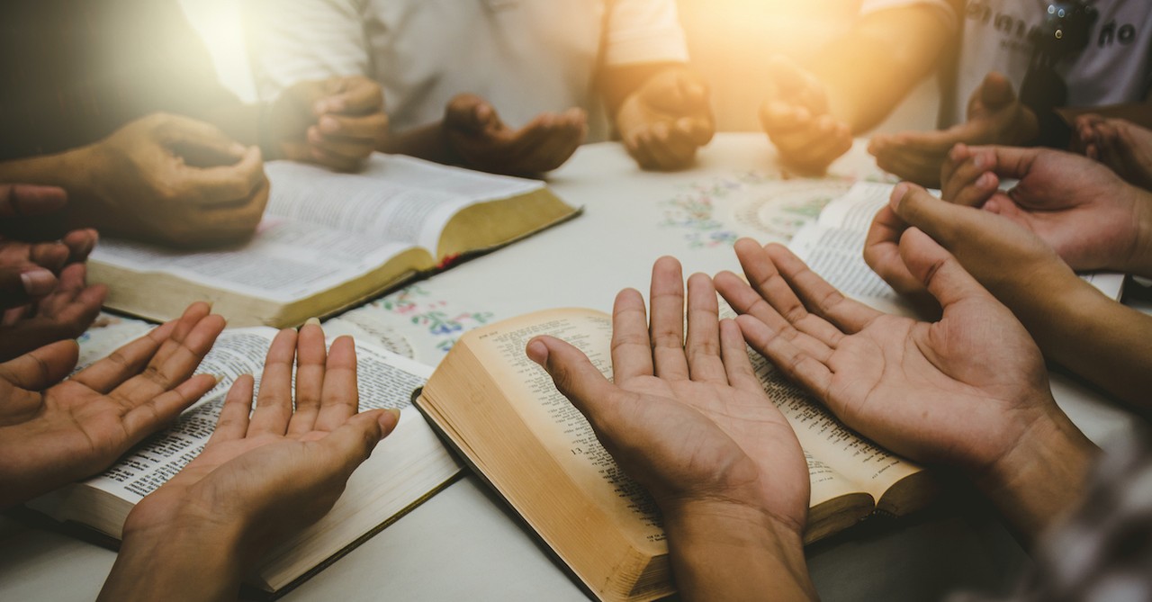 hands held over bibles, prayer for missionaries