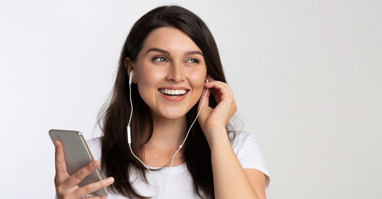 woman listening to earbuds music podcast happy smiling content