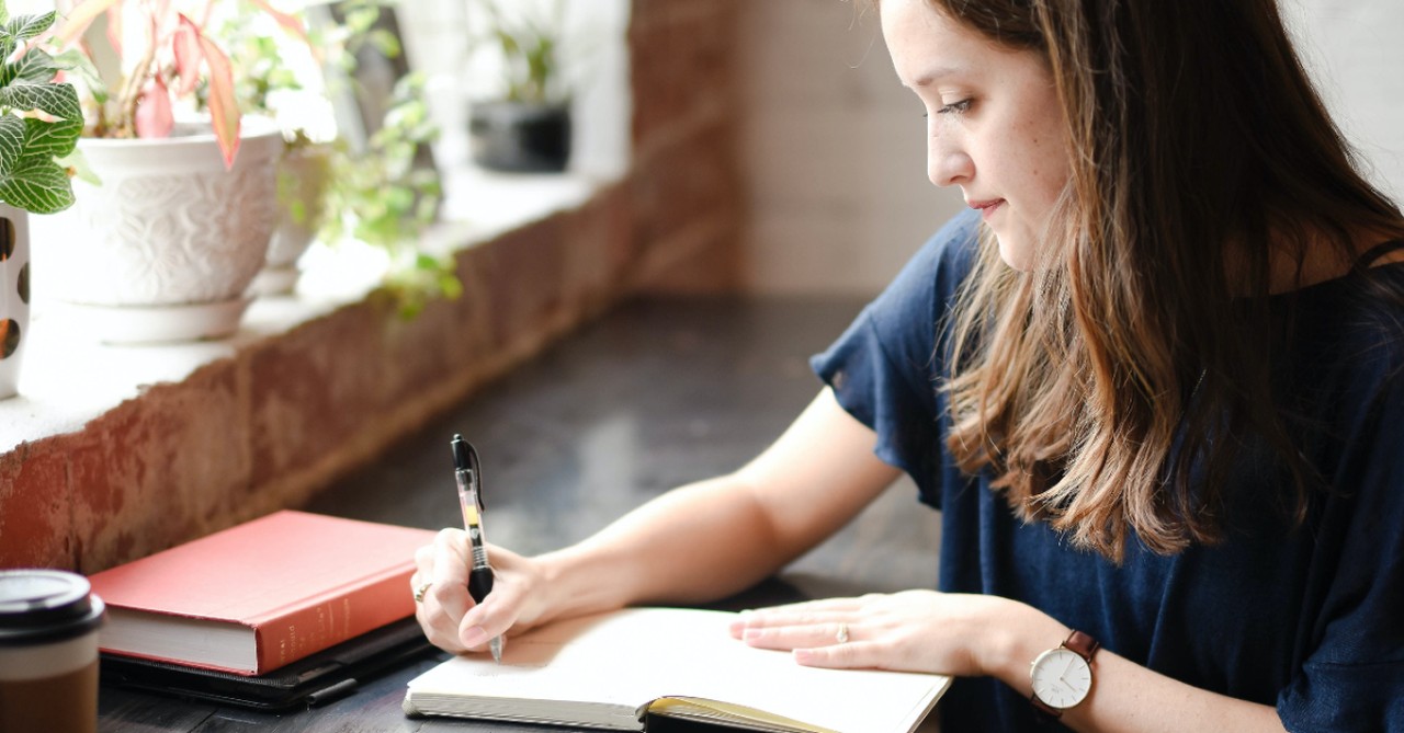 woman journaling in coffee shop