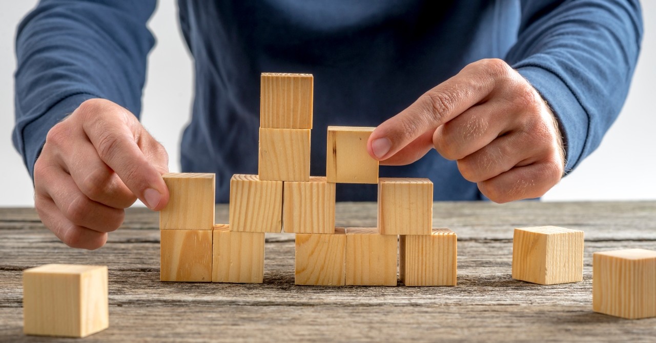 Man building an uneven tower of blocks