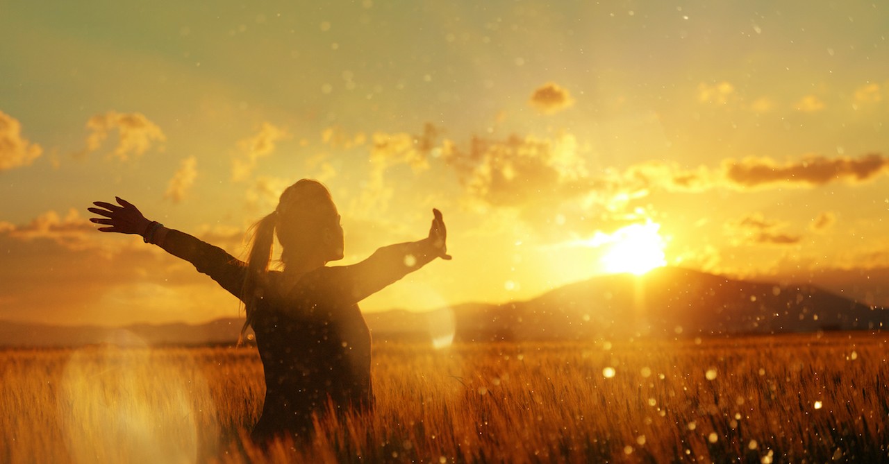 silhouette of woman praising in a field at sunset, grow in grace