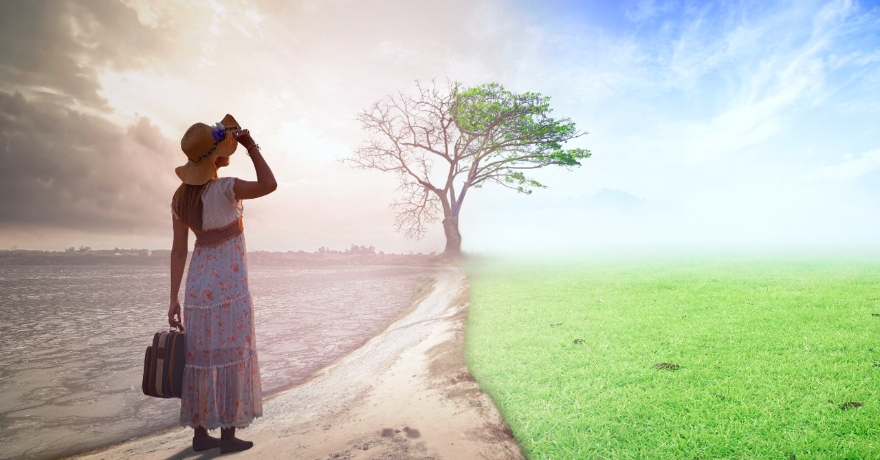 Woman in the desert looking at green grass and blue sky