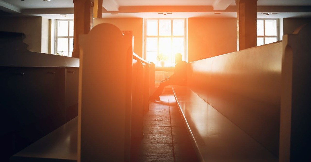 man sitting in pew church pew sunset window light