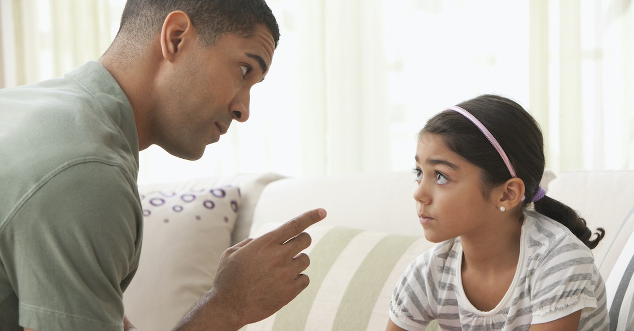 father disciplining young daughter by pointing finger at her in conversation, spare the rod spoil the child