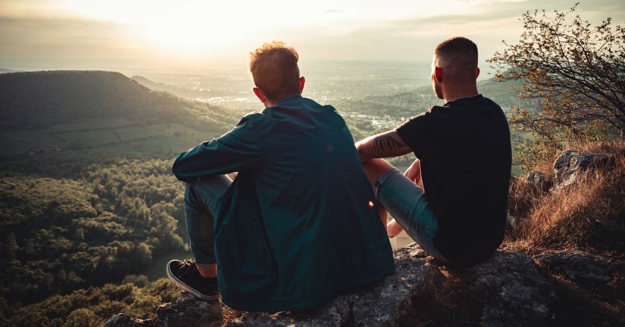 two guy friends sitting on mountain