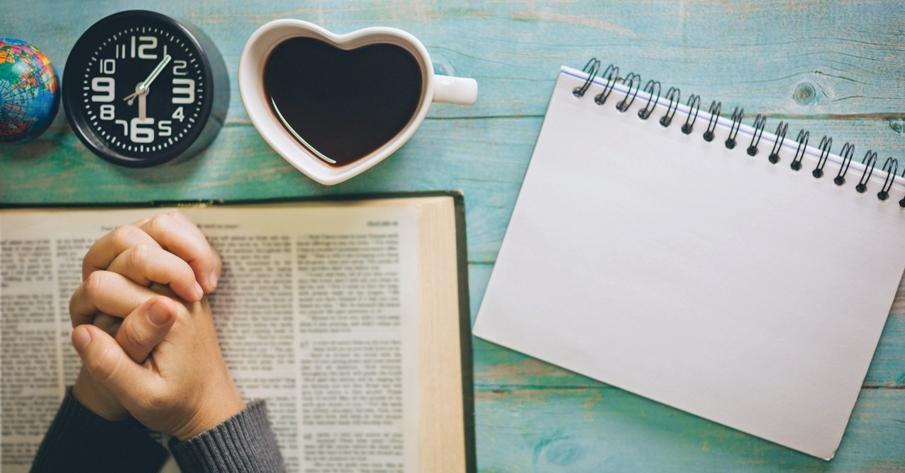 Bible, coffee, notebook, clock, and desk