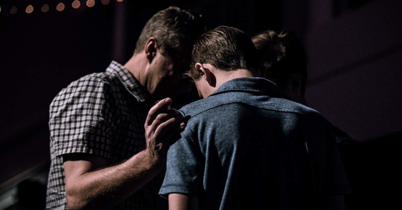 Men standing in a circle praying together