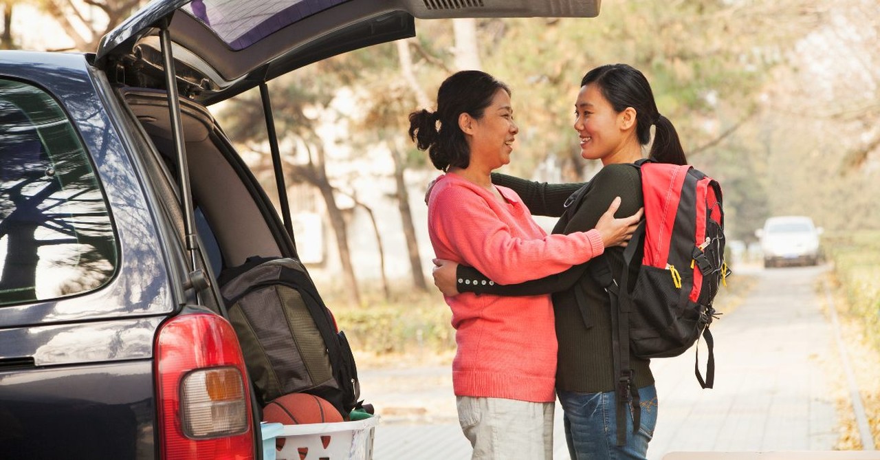 Mother and daughter embracing in front of a packed car