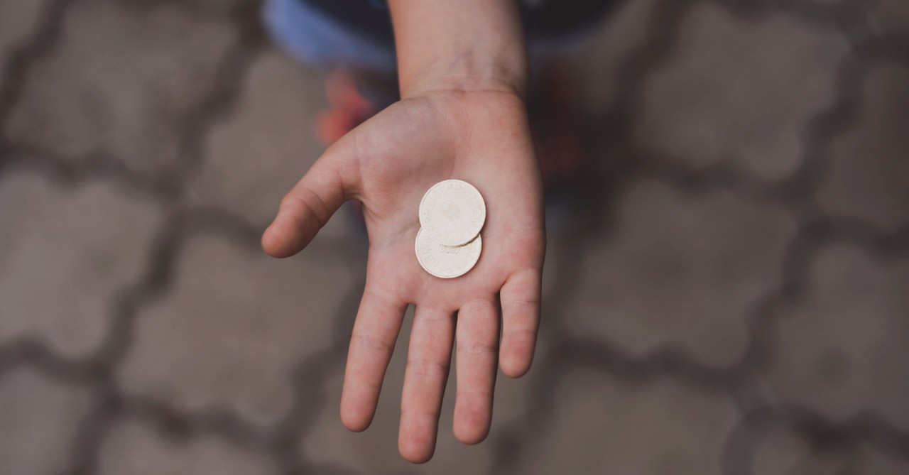 two gold coins in a person's open hand