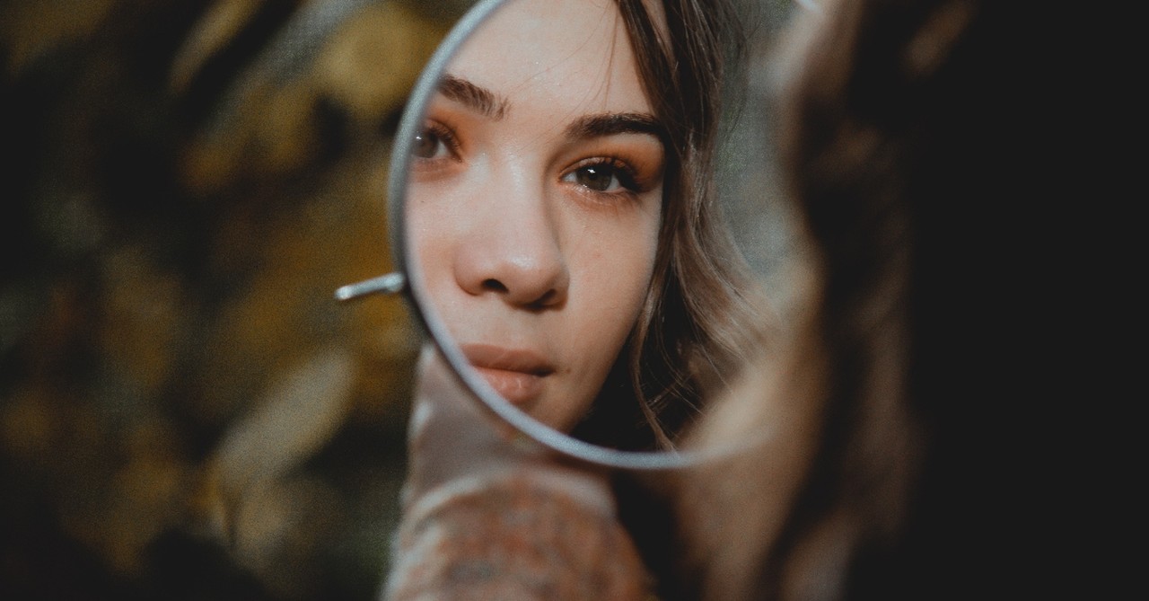 girl looking in small mirror outdoors