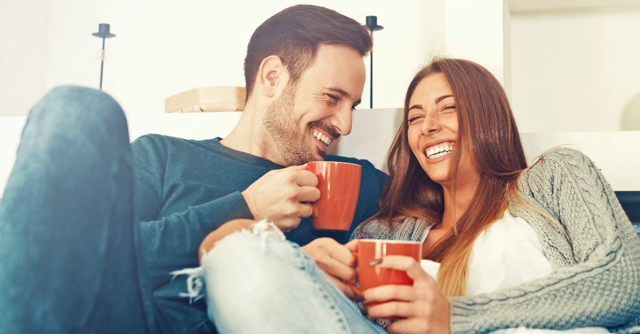 Husband and wife talking on a couch with coffee