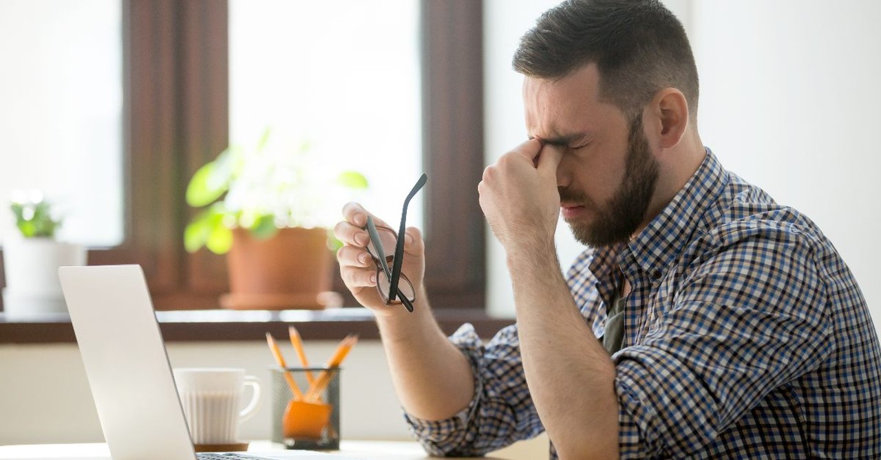 An exhausted man in front of his laptop