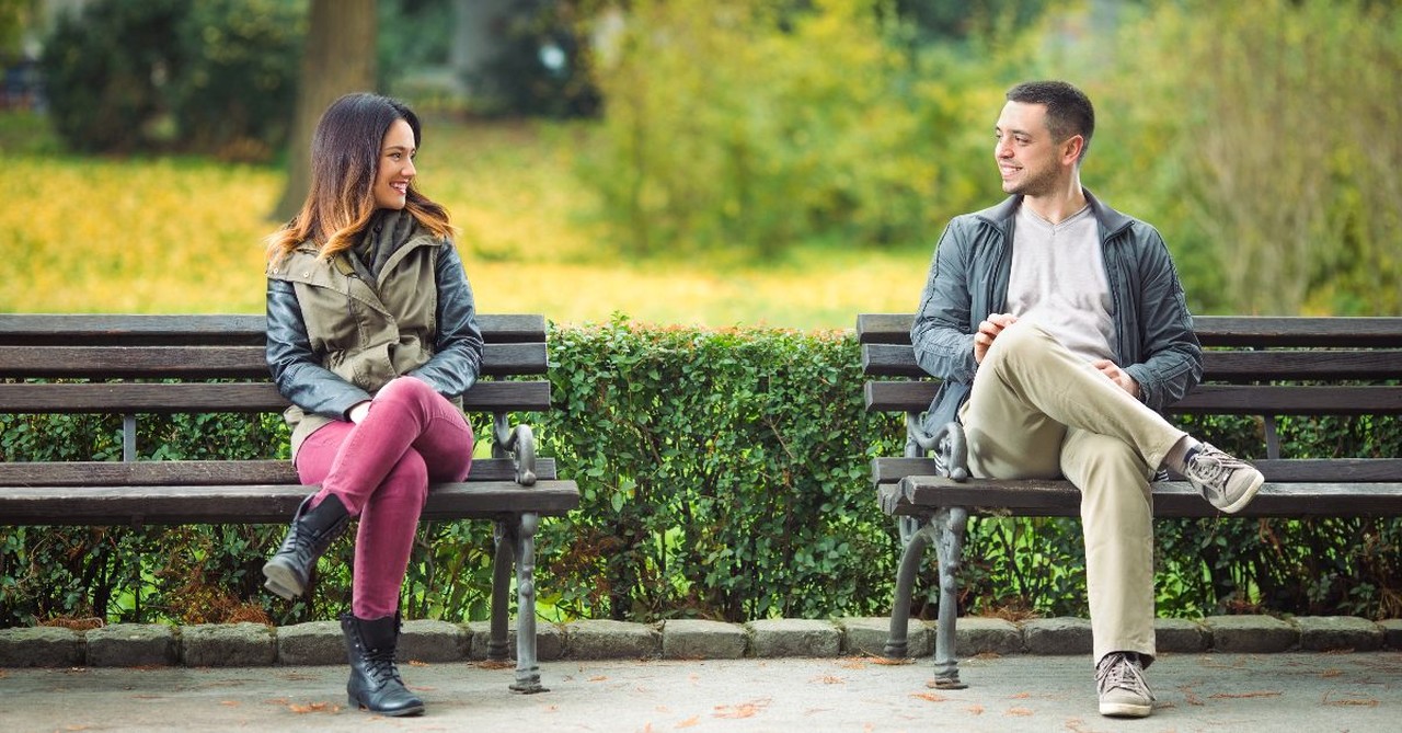 Man and woman looking at each other from their park benches