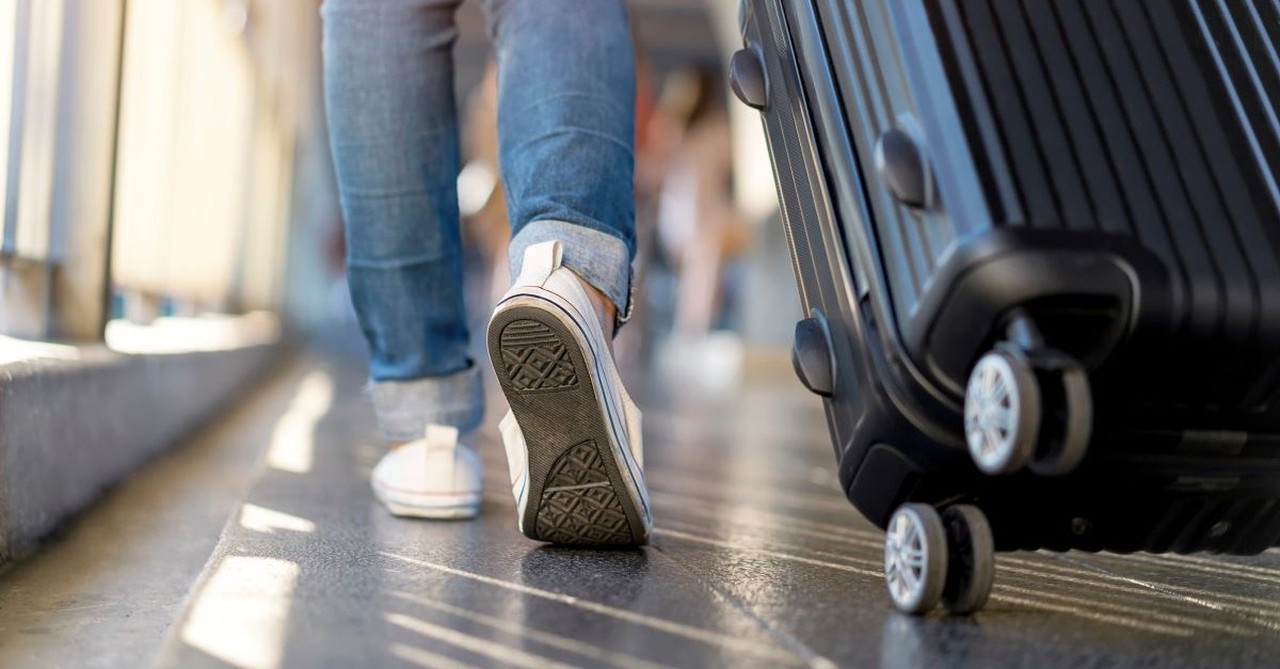 Woman walking at the airport with rolling luggage