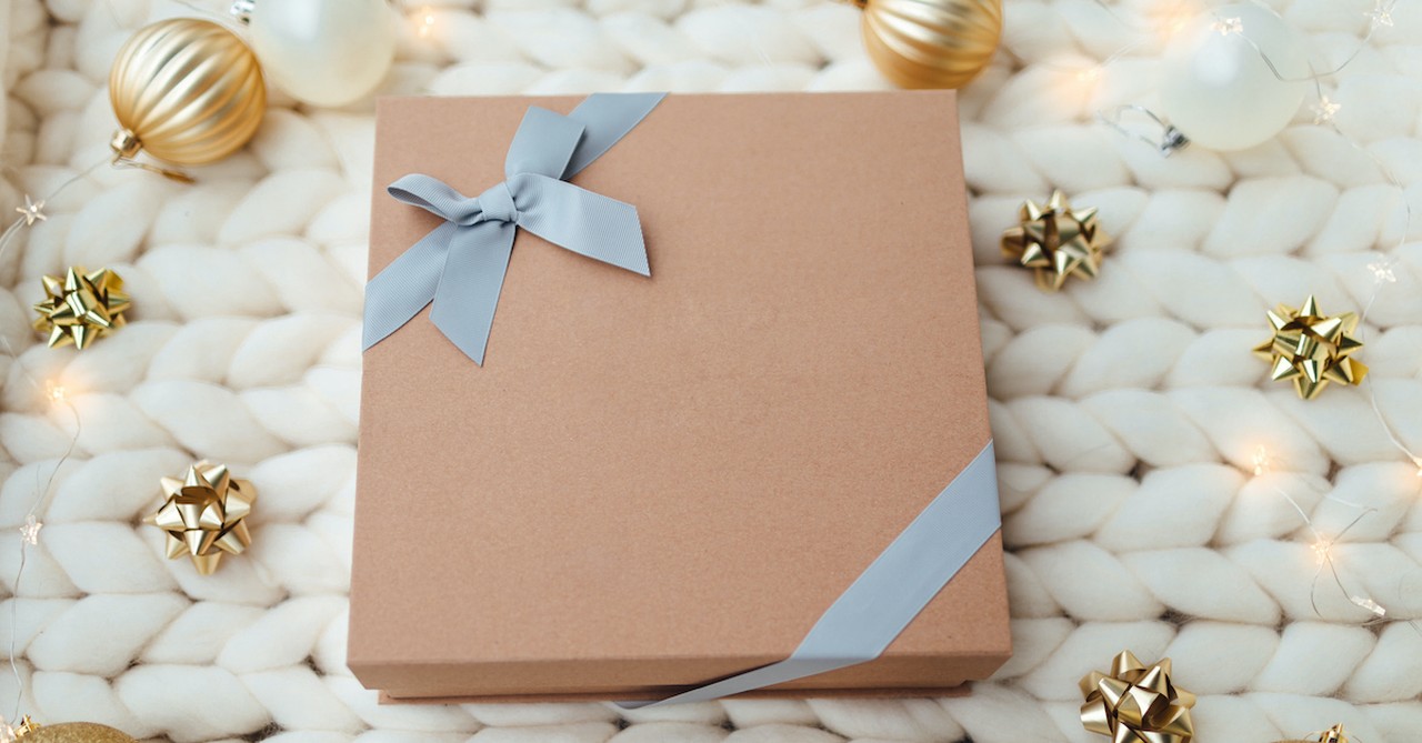 Christmas gift on white blanket with bows and ornaments around