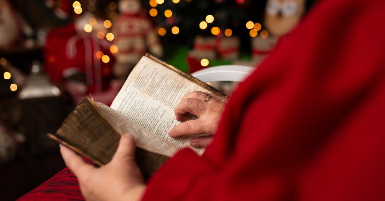 Woman reading the Bible in front of the Christmas Tree