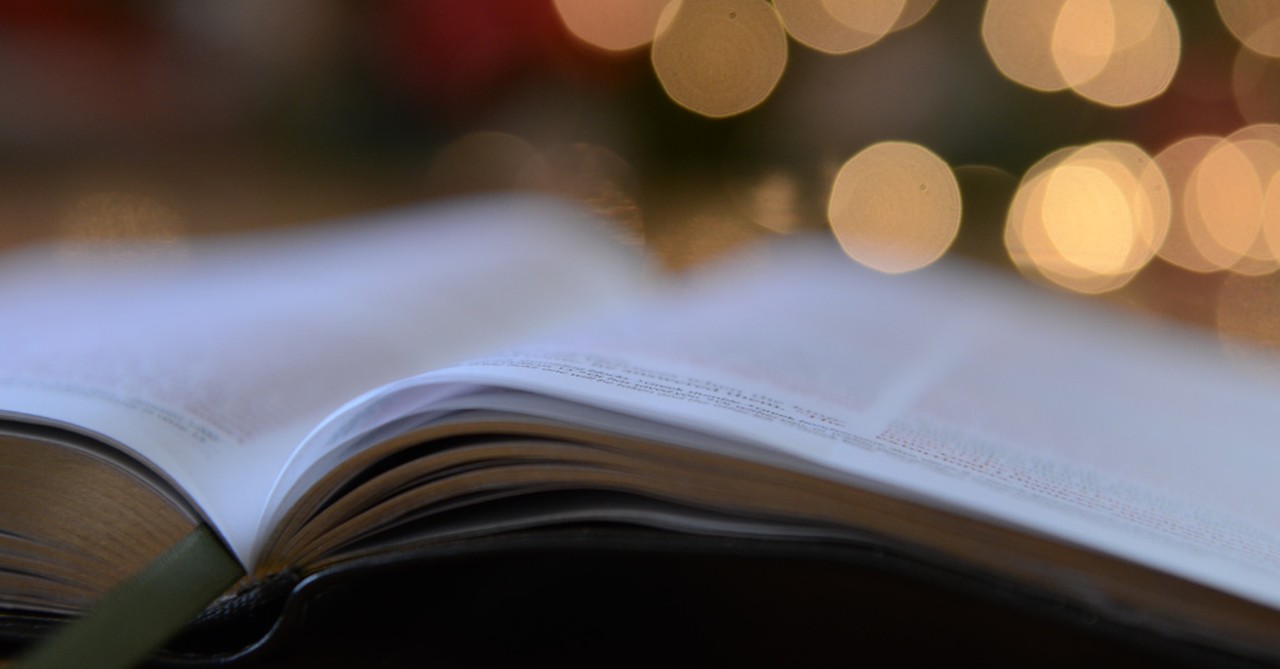 Bokeh Christmas lights and a Bible, We must celebrate the baby and not just the holiday