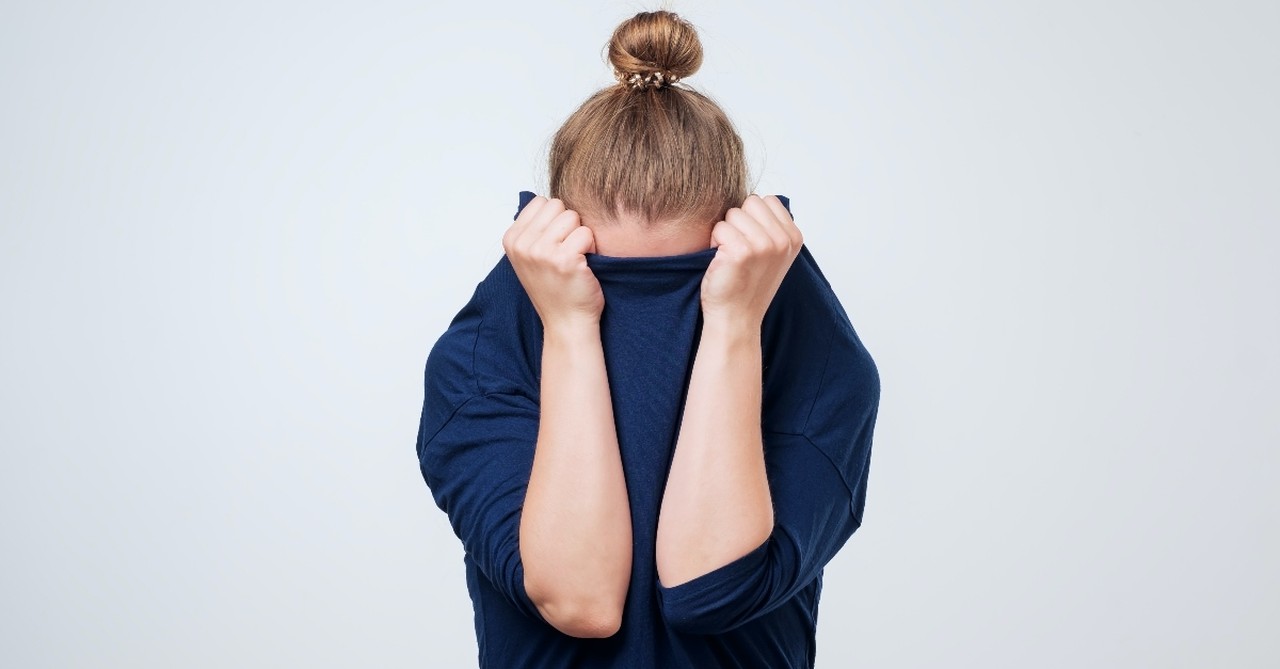 Woman pulling her shirt over her head in fear