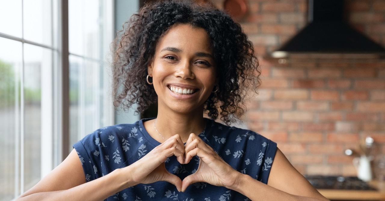 Woman smiling with her hands in the form of the heart