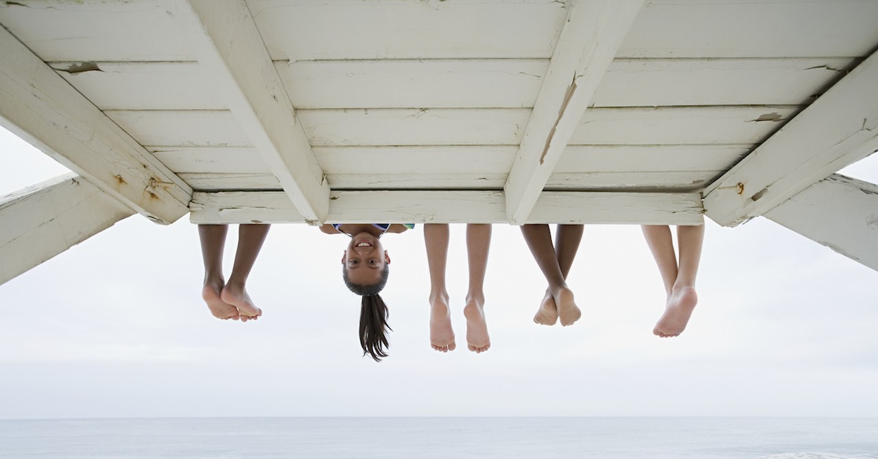 feet hanging down above water with one little girl leaning down smiling
