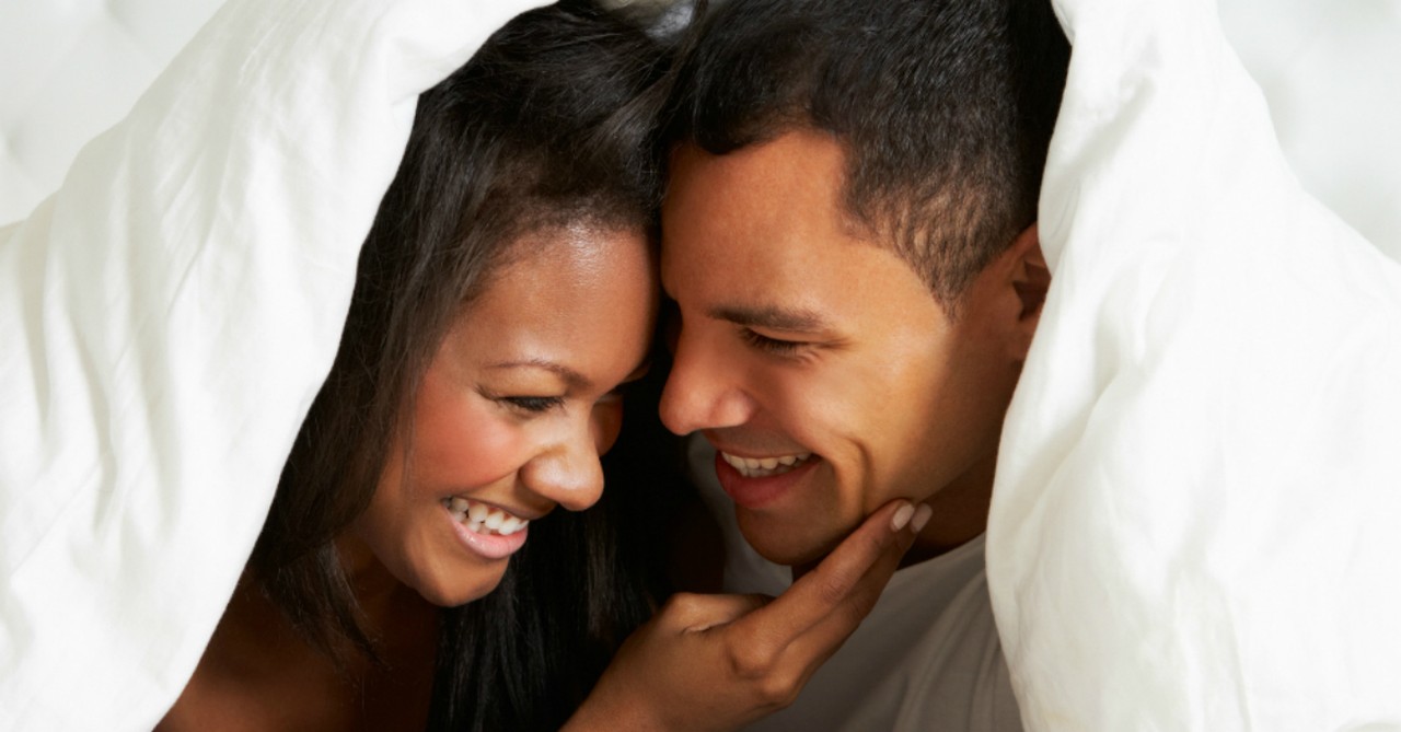 Happy couple snuggling under the covers