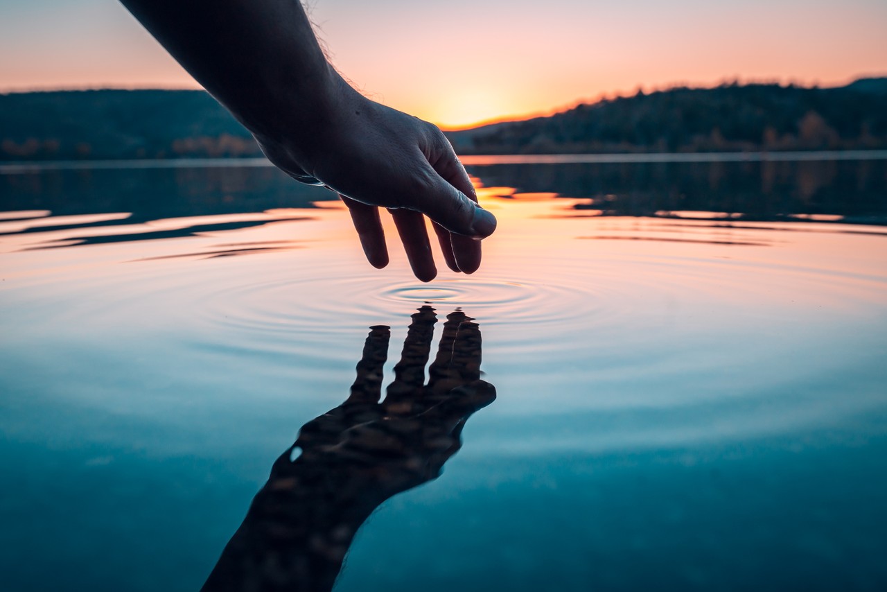 hand touching water as sunset, hymns to silence satan's lies