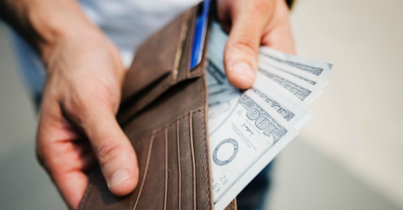 man opening wallet with cash inside