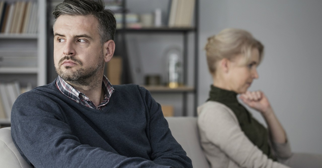 mature couple sitting upset looking away from each other on couch, shame undermines marriage