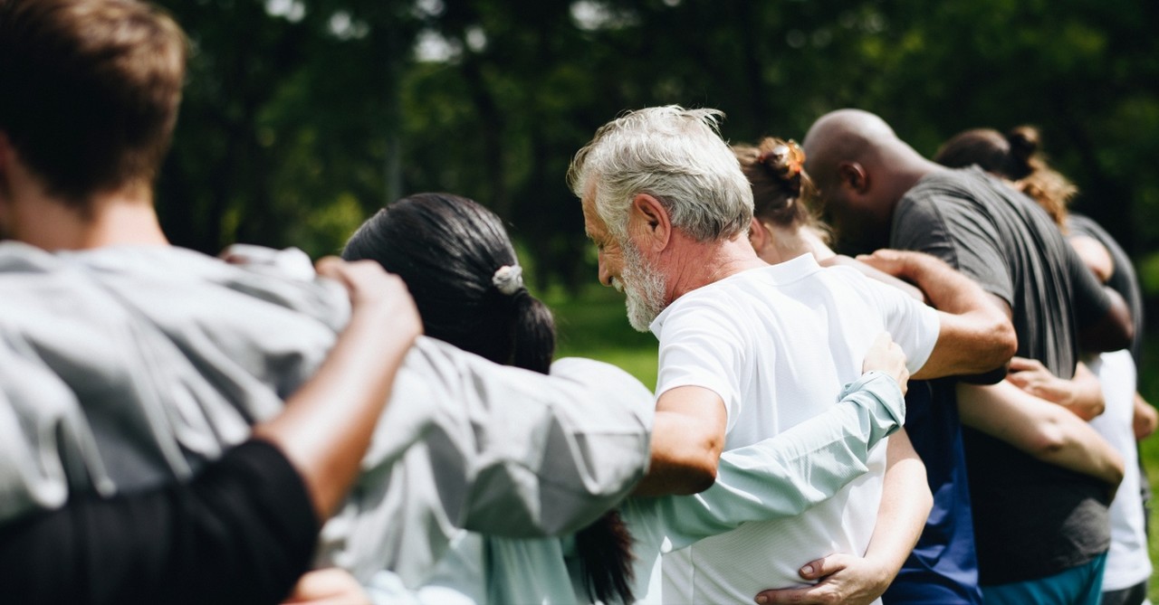 diverse group hug praying love because he first loved us