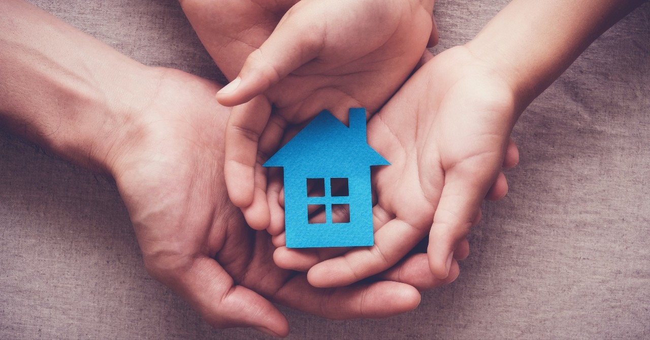 hands in pile holding paper house symbol