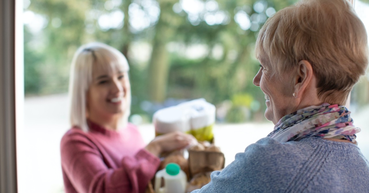 A woman bringing groceries to another woman's house