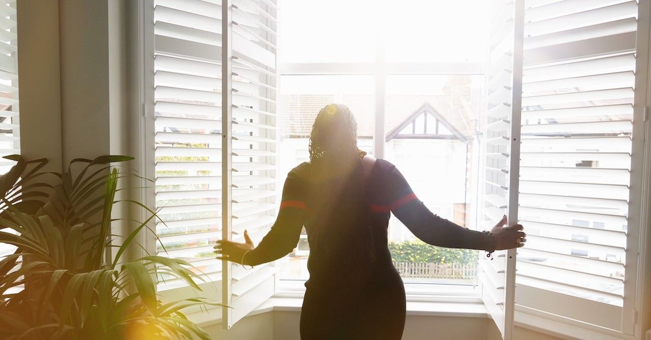 silhouette of hopeful woman looking out bright window