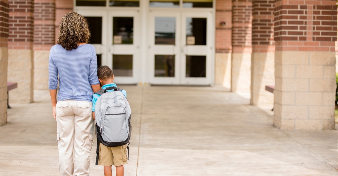 Mom and young son standing anxiously outside a school building