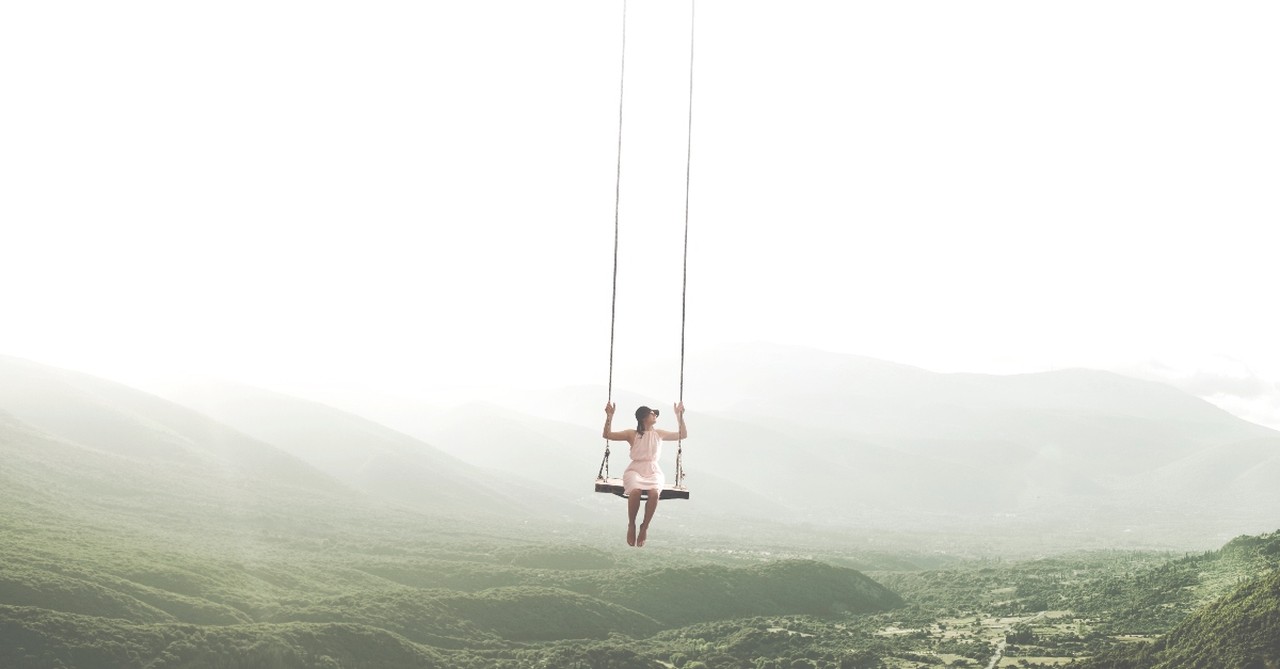 Woman hanging on swing over a valley